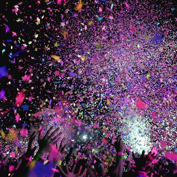 Image représentant l'ambiance d'un concert (mains levées et confettis) 